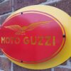 Handmade red and yellow oblong-shaped sign with the Moto Guzzi logo.